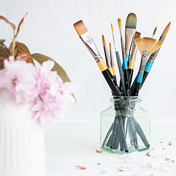 Paintbrushes and pink floral blossom in vase image